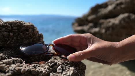 mujer colocando gafas de sol en la roca y yendo a nadar en la playa, estado de ánimo de verano de vacaciones