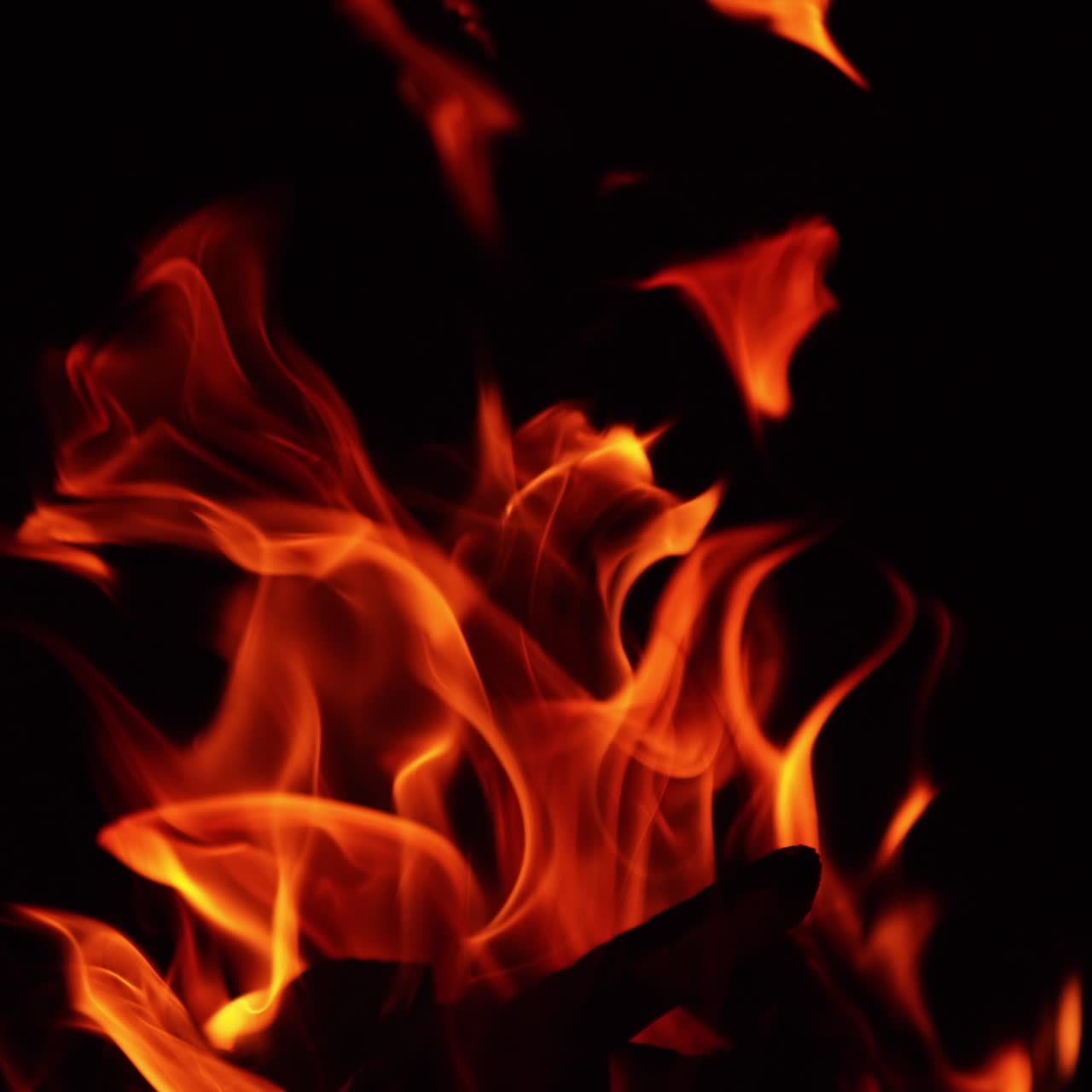 Legna accatastata che brucia nel falò. Le fiamme si muovono lateralmente di notte. Primo piano.