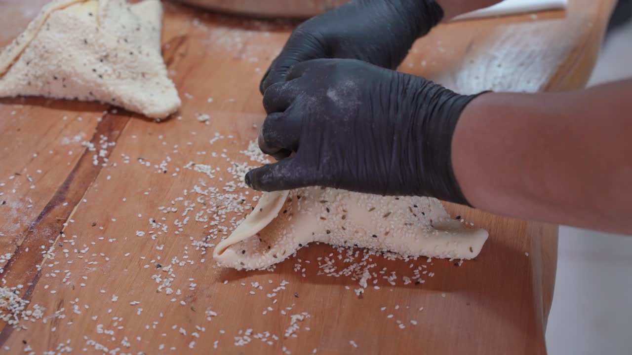 un chef de pastelería pellizca juntos los bordes de la masa cruda mientras da forma a los pasteles flaouna