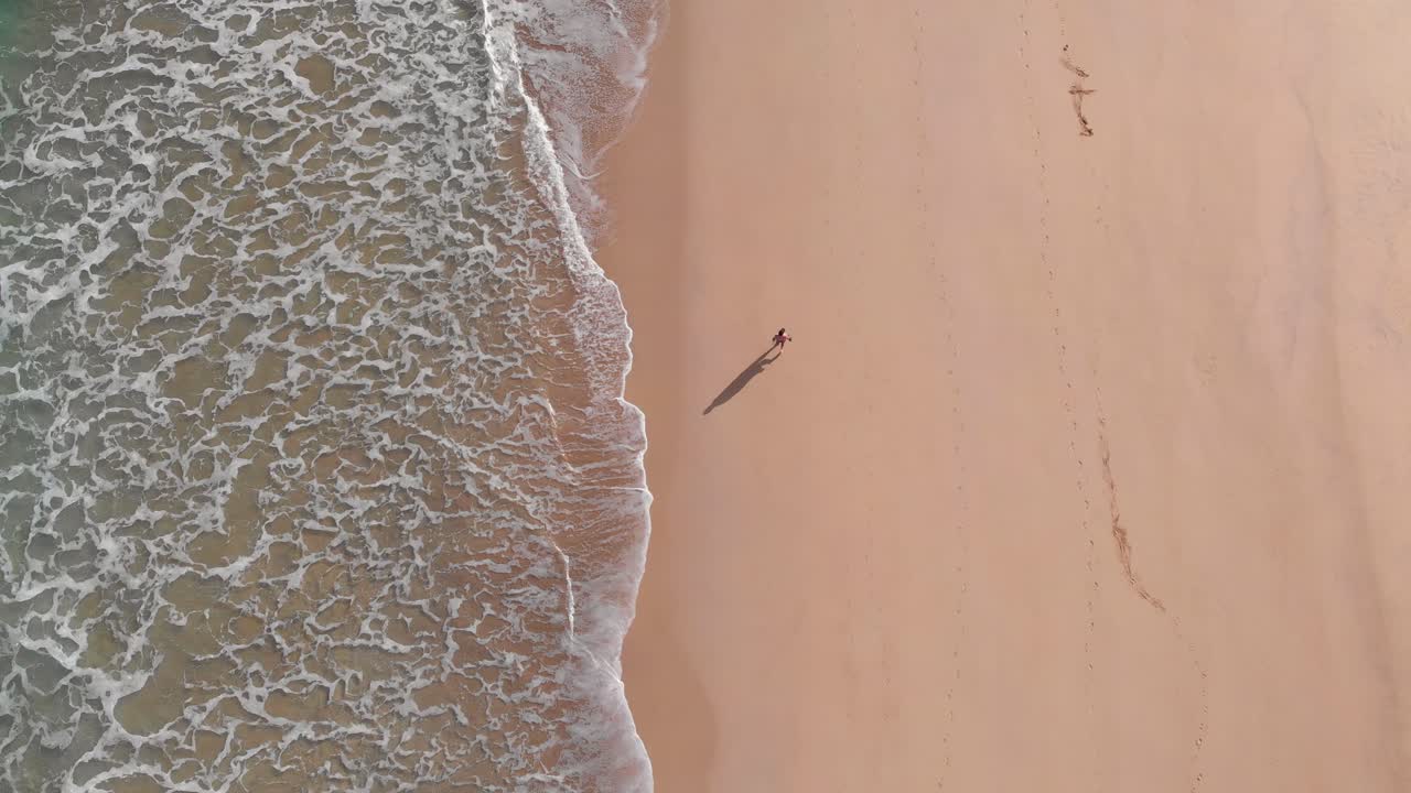Una persona solitaria cammina da sola su una spiaggia dorata sull'isola di Porto Santo, Portogallo.