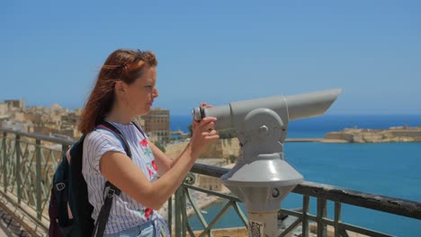 mujer joven usa los binoculares turísticos para ver las vistas de valletta malta y las tres ciudades