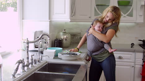 busy mother with baby in sling at home shot on r3d