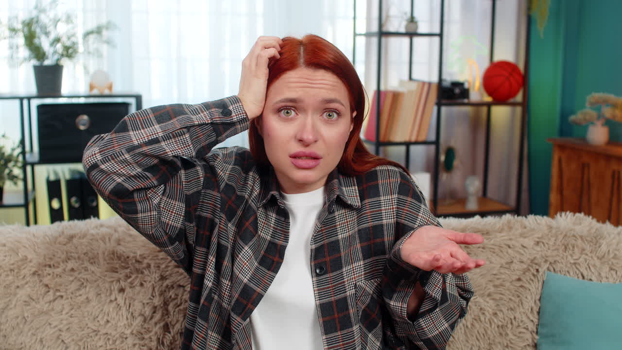 Woman sitting on sofa holding head looking confused and lost not knowing what to do in hard moment