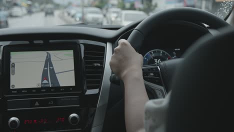 mujer conduciendo un coche con pantalla de mapa para navegar en la carretera urbana.
