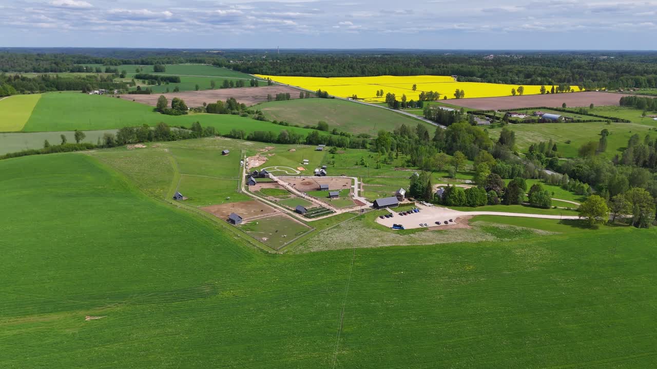 Aerial orbit small petting zoo complex with buildings and animal pens surrounded by farmfields