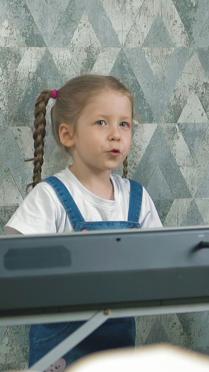 slow motion little child plays on electric piano at home during pandemic, sings sad song, makes final chords, wide hand gesture