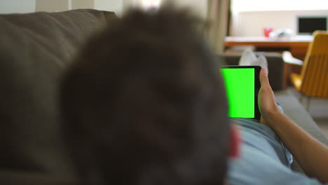 man relaxing on a couch with a tablet