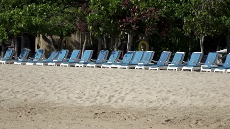 waves of the warm sea run on the sandy beach of the tropical resort with umbrellas and chaise lounges