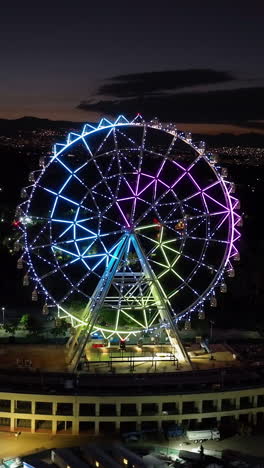 portrait drone shot toward the illuminated ferris wheel at aztlan park, cmdx