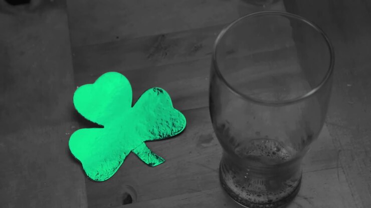 Hand putting down empty pint beside large green shamrock