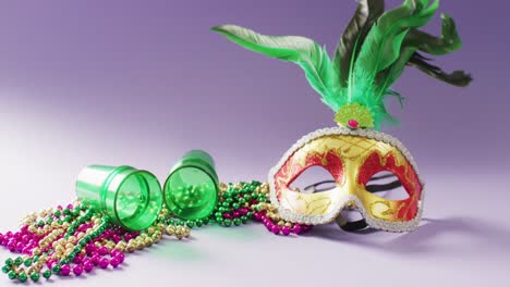 video of carnival masquerade mask with green feathers, mardi gras beads and shot glasses, copy space