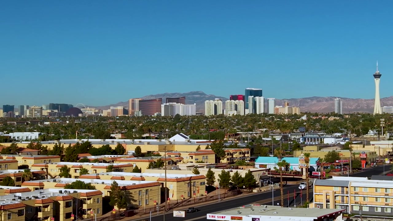 Dronen fejer langsomt fra venstre mod højre, med den berømte Las Vegas skyline som baggrund for en udstrakt og voksende Las Vegas-forstad.