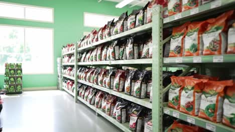 a well-organized aisle in a plant nursery featuring various bags of soil and nutrients for gardening enthusiasts and professionals