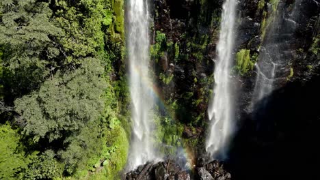 Cascada-Doble-Con-Un-Arco-Iris-Escondido-En-Un-Bosque---Disparo-De-Drones