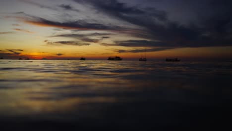 sunset over the ocean with silhouetted boats