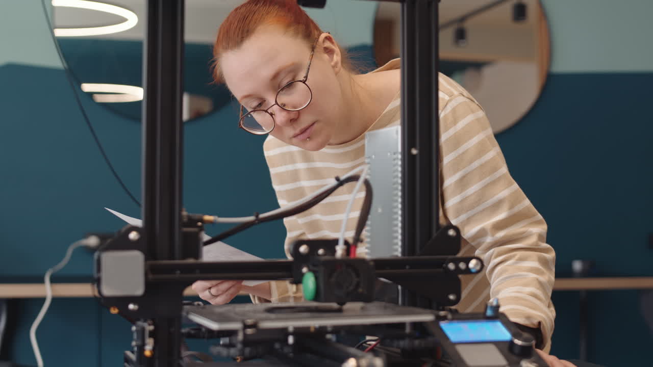 Young Woman Watching 3D Printer Working