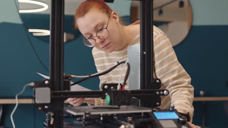 young woman watching 3d printer working