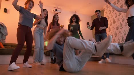 happy friends cheering for man performing stunt on floor during weekend party at home
