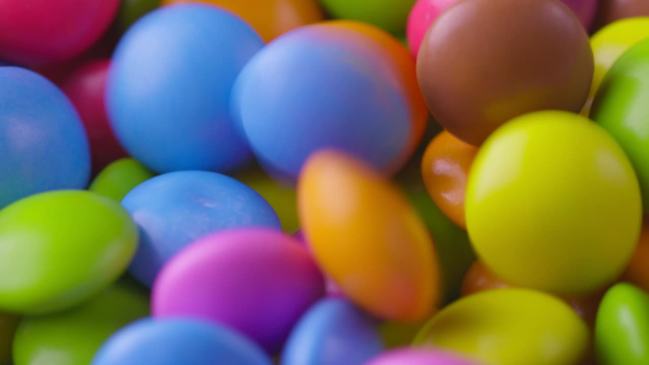movimiento lento de primer plano de caramelos de chocolate redondos de colores, dragee. rotación y caída de caramellos de chocolate multicolores