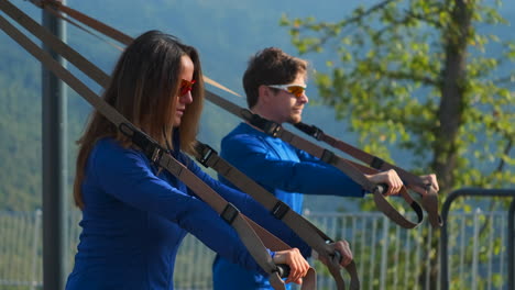 pareja trabajando con equipos de entrenamiento de suspensión al aire libre