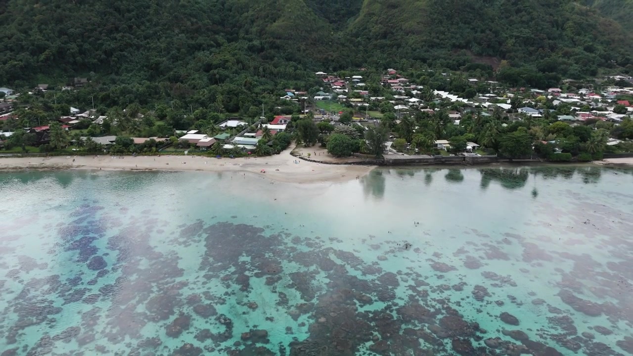 Città costiera con sabbia bianca sulla spiaggia di Plage Vaiava a Puna'auia, Polinesia Francese. Ripresa aerea con allontanamento.