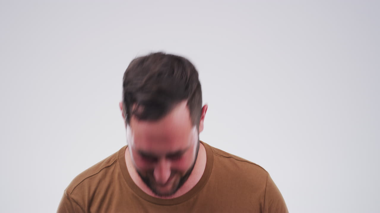 un joven riendo contra un fondo gris