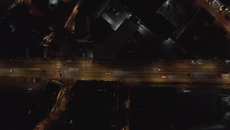 light traffic on asphalt road in city at night - aerial top down view