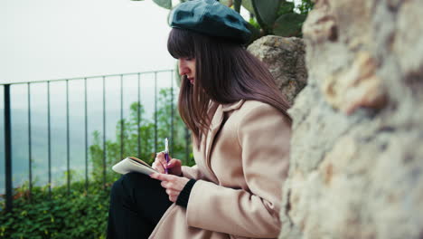 woman sitting in the town street taking notes with a pen