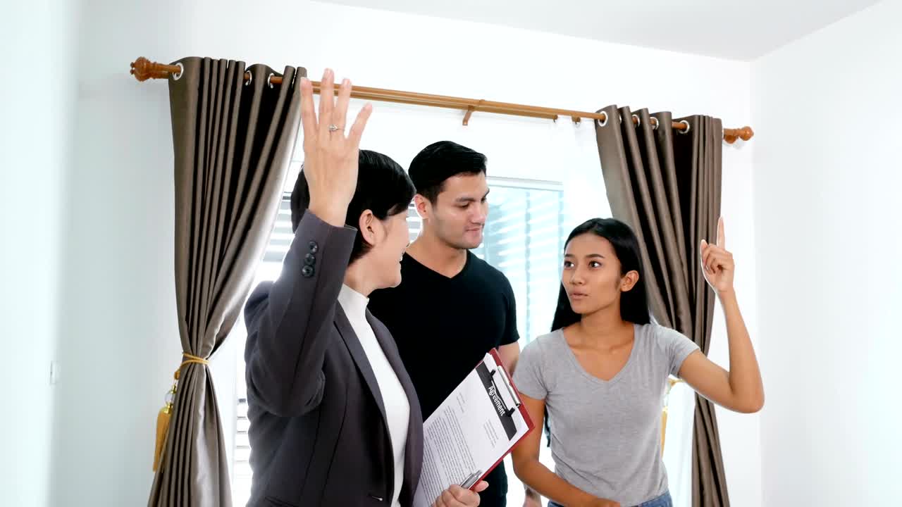 새로운 집을 구입하거나 임대하려는 젊은 부부. 전문 부동산 에이전트가 고객에게 현대적인 집을 제시합니다. 4k 해상도.