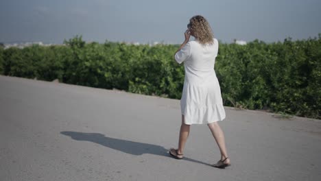woman walking on a road through a tree plantation