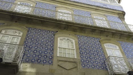 patterned purple yellow geometric circle shapes cover side of building between window sill openings