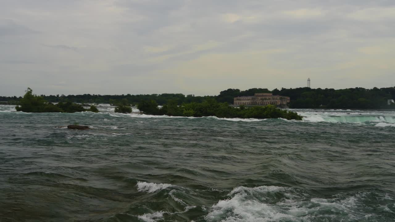 A dramatic view of the river approaching the brink of Niagara Falls, with mist rising high and the relentless power of nature captured from a breathtaking perspective