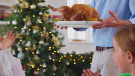 Familia-Multigeneracional-Celebrando-La-Navidad-En-Casa-Con-El-Abuelo-Sirviendo-Pavo