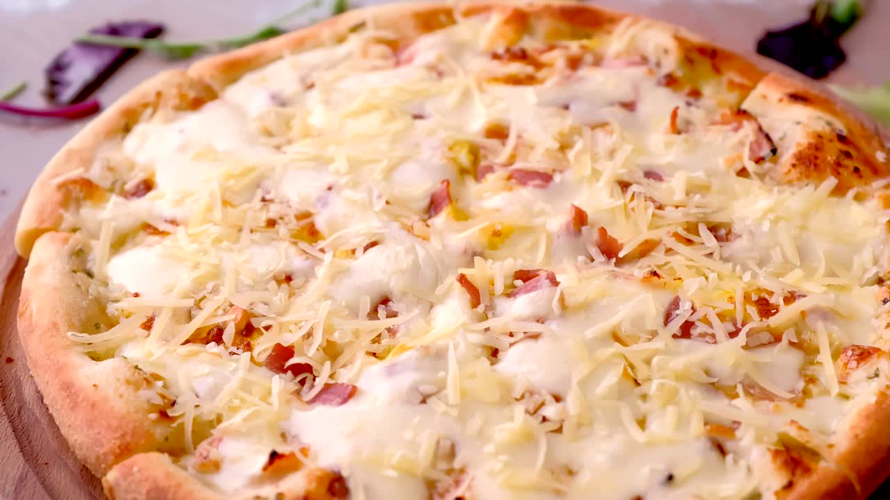 Chef sprinkle bacon pizza grated cheese.