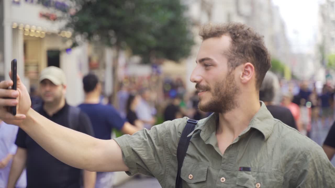 hombre haciendo una videollamada en una concurrida calle de la ciudad.