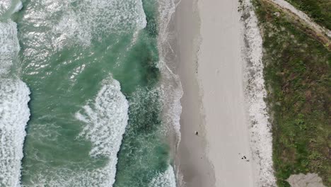 Vista-Aérea-De-Drones-De-Olas-Espumosas-En-La-Costa-De-Arena-Blanca