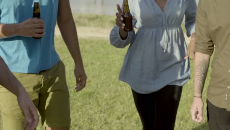 cropped shot of friends clinking beer bottles and dancing