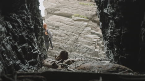 a person exploring a cave and emerging into a rocky landscape