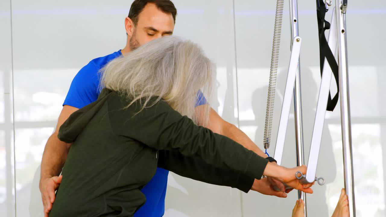 entrenador ayudando a una mujer mayor en la realización de yoga 4k