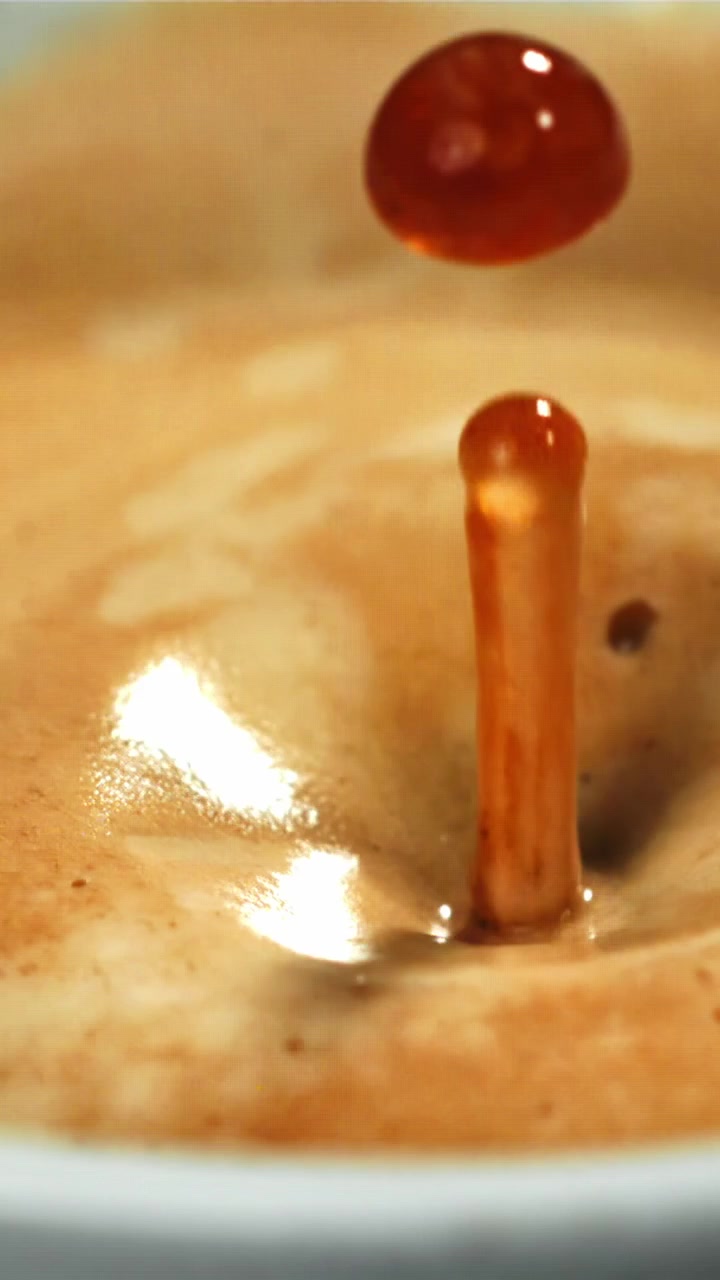Movimento rallentato di una goccia di caffè che si tuffa nella crema dell'espresso