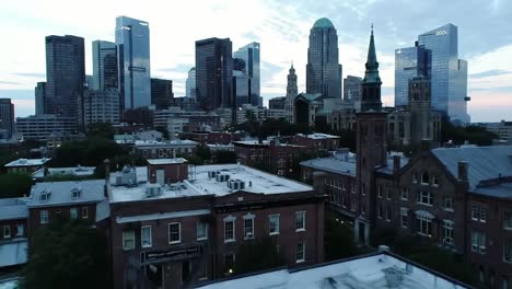 aerial view of a cityscape at dusk, highlighting a blend of modern skyscrapers and historic buildings surrounded by a peaceful urban atmosphere