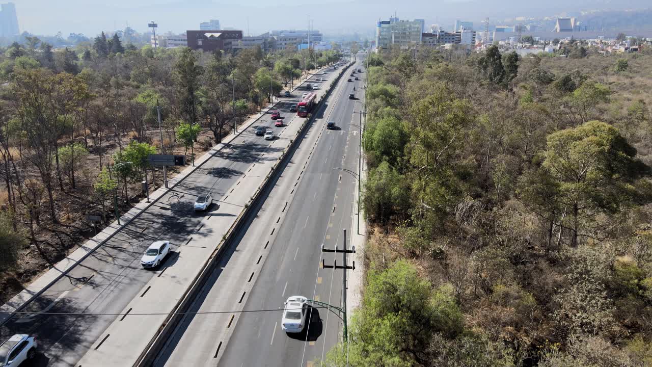 Aerial View of a Busy Urban Highway with Traffic, Trees, and City Buildings