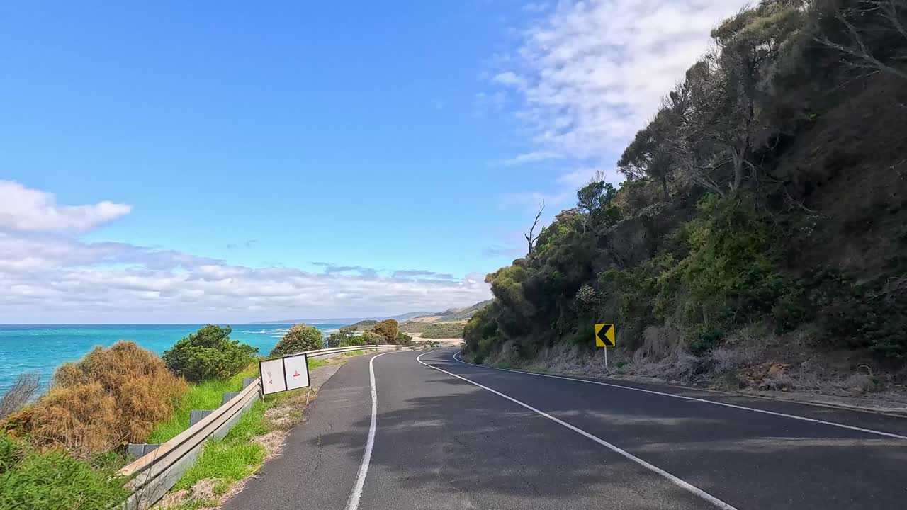 A 14-second video captures a serene drive along the Great Ocean Road, showcasing coastal views and lush greenery under clear skies