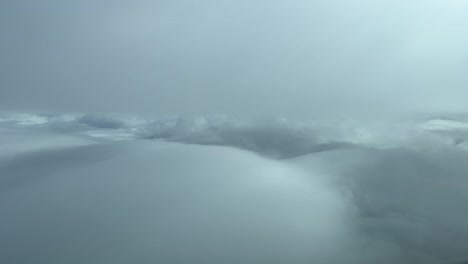 aerial view from a jet cockpit while flying between layers of soft white and grey clouds