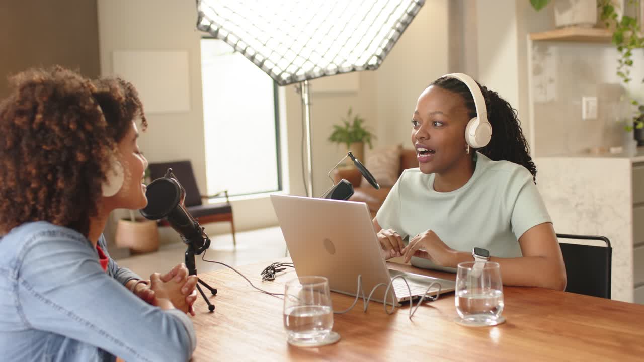 Co-conduttrici diverse che ricevono spunti di conversazione, regolano i microfoni e gesticolano in uno studio domestico