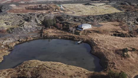 Icelandic-cabin-with-lake,-revealing-suburban-area-of-south-Reykjavik,-aerial