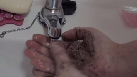 lavarse las manos sucias bajo el grifo de agua corriente