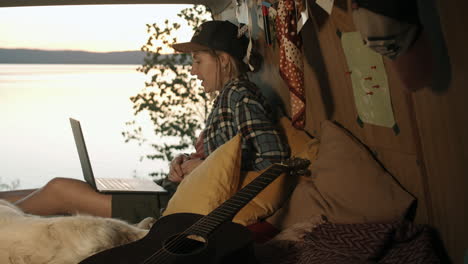 woman chatting on video call on laptop in camper van