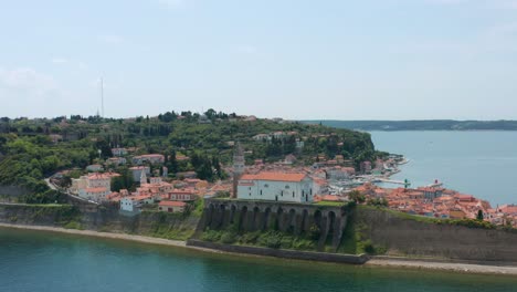 aerial arc shot pulling away from the city of piran, slovenia on a bright summer day