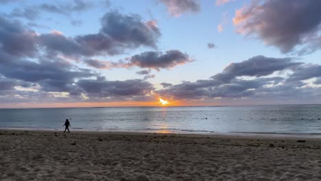 person silhouetted against a stunning sunset on a tropical beach